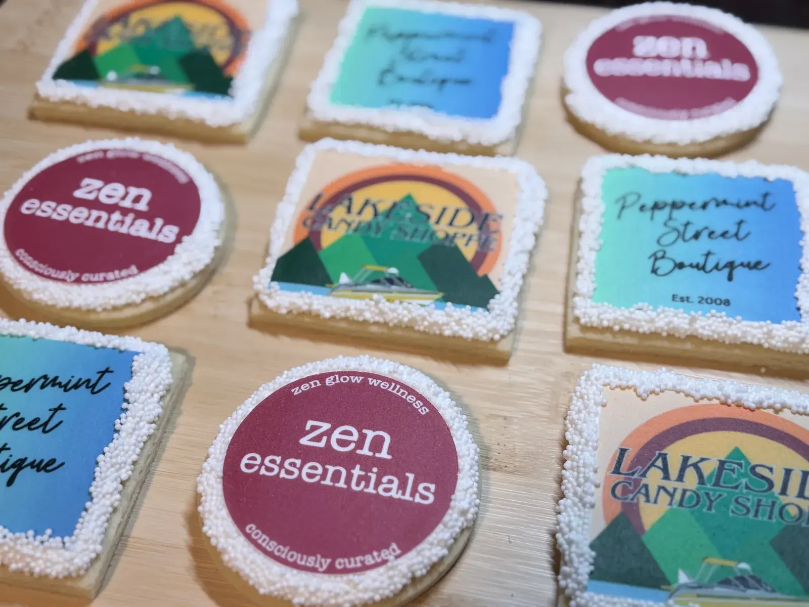 A closer view of the same logo cookie set, showing the Lakeside Candy Shoppe lakeside-mountain design and the Zen Essentials circular logo in detail.